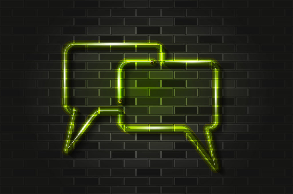 Neon speech balloons in light green, on a dark brick wall